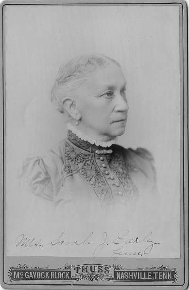Formal bust portrait of a woman in three-quarter profile. Her hair is pinned back, and she wears a dress with a dark bodice and decorative applique.