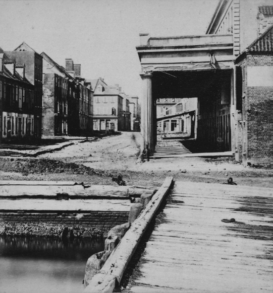 A road with storefronts and houses on either side.