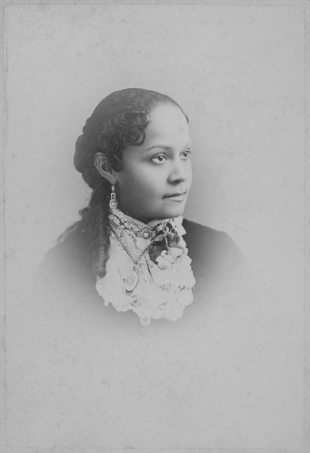 Formal bust portrait of a young woman. She wears a dress with a dark bodice and lace trim, and fine jewelry.