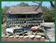 A row of sea grass baskets sits on a low brick wall. More baskets sit on tables and line the front porch of the building in the background.