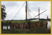A wooden ship docked along the banks of a river.