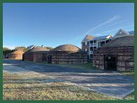 Three round buildings surrounded by piles of bricks.
