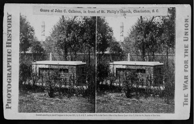 Stereograph of brick and stone aboveground tomb with trees and church steeple in background.