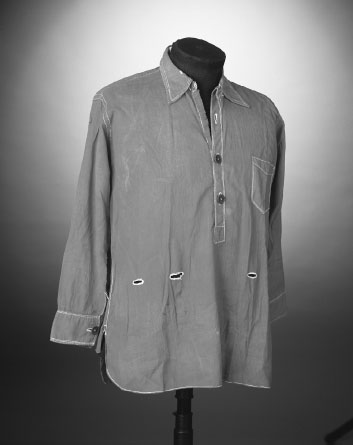 A long sleeve collared shirt with two buttons and three holes in the torso displayed on a headless mannequin.