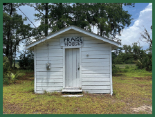 A small clapboard building with a sign above the door that reads, “Praise House.”