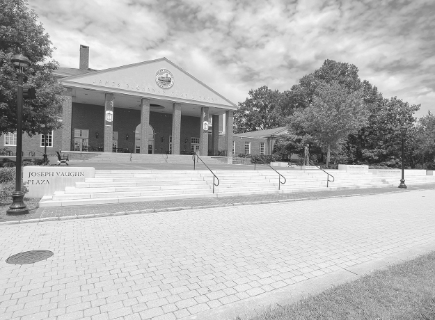 Figure 9. Brick-lined path at the foot of tiered steps with sign stating Joseph Vaughn Plaza. Steps lead to open space in front of a large building and trees.