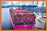 A large cargo ship docked at port. It is loaded with many multi-colored shipping containers.