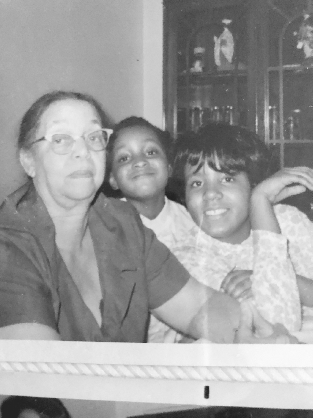 Figure 2. A woman and two children sit at a table with a china closet in background.